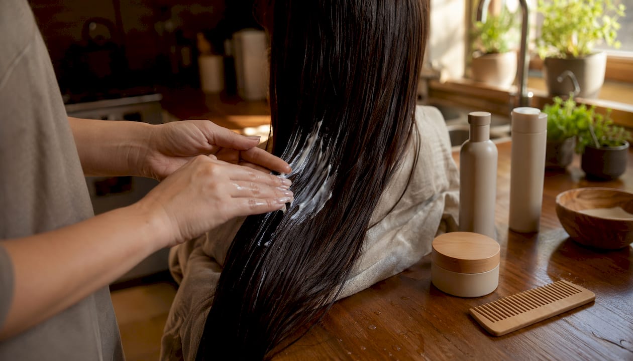 Hands applying smoothing serum to hair strands