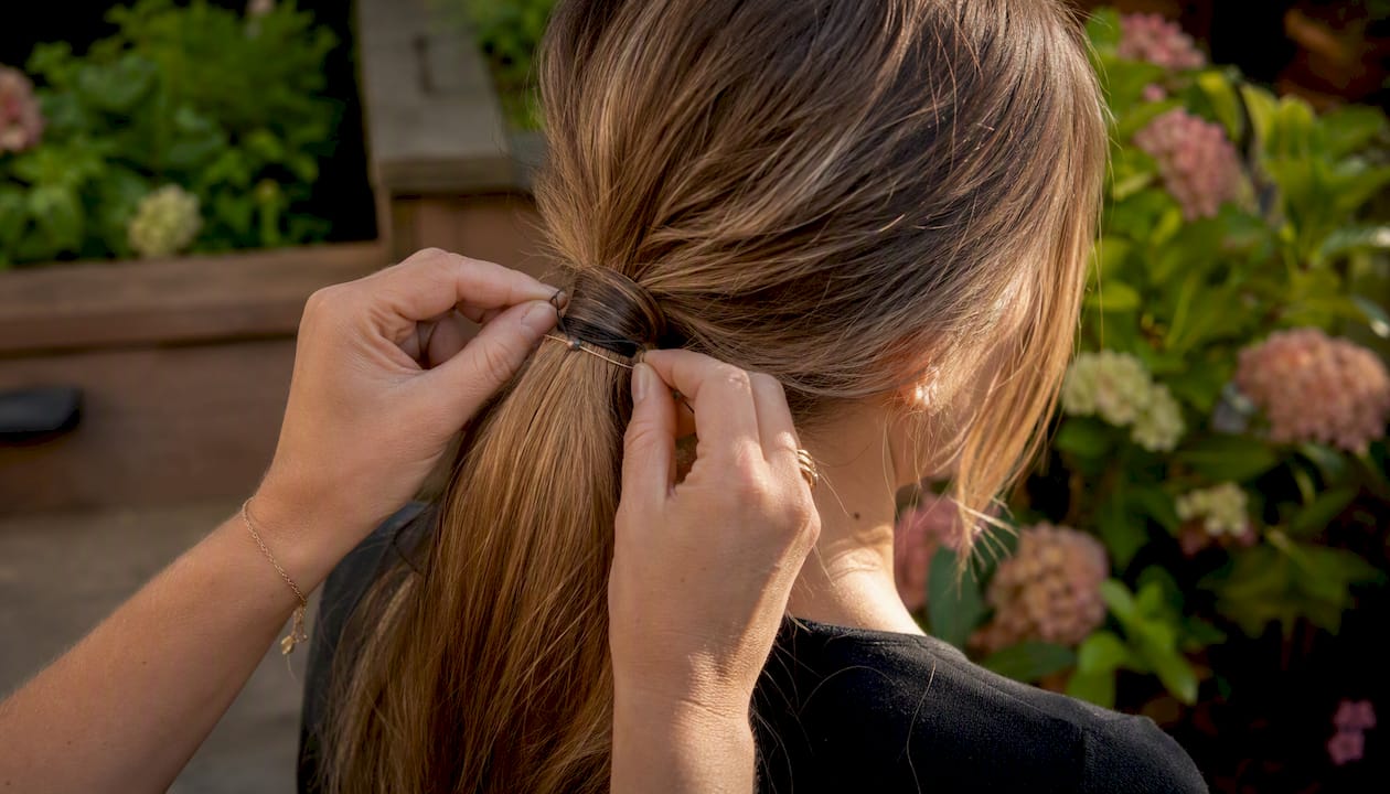 Hands attaching lightweight ponytail to fine hair