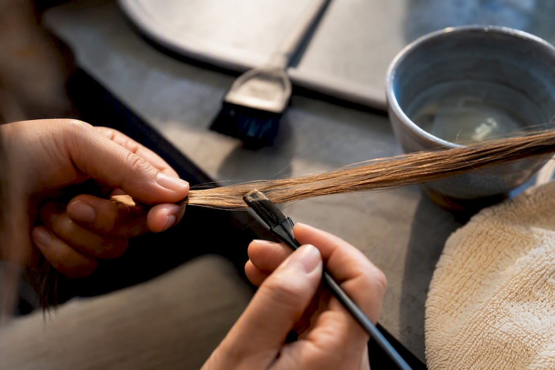 Hands testing colour on a small hair strand
